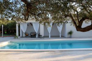 a swimming pool in front of a house with a tree at Villa Amber in Supetar