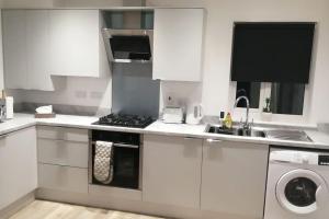 a white kitchen with a stove and a sink at Lovely 1-Bedroom Flat in Hinckley, LE10 in Hinckley