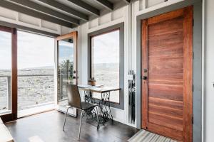 Zimmer mit einem Tisch, Stühlen und einer Holztür in der Unterkunft THE PHOENIX HOUSE - EPIC Tiny Home Gem on Volcanic Lava Field! in Kehena