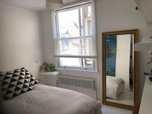 a bedroom with a mirror and a bed and a window at Stunning Richmond Maisionette with rooftop patio in Richmond