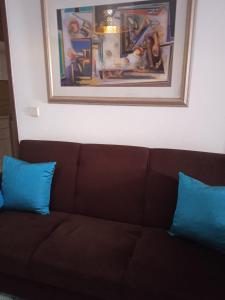 a brown couch with two blue pillows under a painting at Orlanda Veríssimo in Nazaré