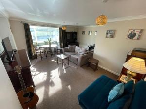 a living room with a blue couch and a guitar at Charming Countryside Cottage Ground Floor Apartment in Combeinteignhead Devon in Bishopsteignton