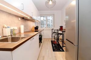 een keuken met witte kasten en een roestvrijstalen koelkast bij Graz central Penthouse Style Apt in Graz