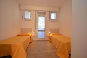 ビビオーネにあるAppartamenti Villa Simonaのオレンジのシーツが備わる客室内のベッド2台