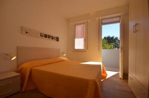a bedroom with a bed with an orange blanket at Appartamenti Villa Simona in Bibione