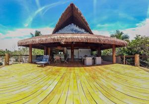 a pavilion with a table and chairs on a wooden deck at Villa Elemental in Marau