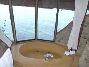 a bath tub in a room with a large window at Mfangano Island Lodge in Mbita