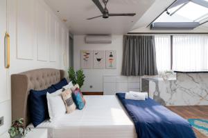 um quarto com uma cama grande e almofadas azuis e brancas em The Moira - Bed and Breakfast em Calcutá