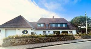 duży biały dom z kamienną ścianą w obiekcie Meer-Lust-Sylt sea cottage lodge w mieście Westerland