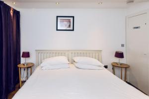 a bedroom with a large white bed with two lamps at Mews House in Brighton & Hove