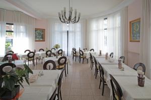 une salle à manger avec tables et chaises et un lustre dans l'établissement Hotel Mignon 50 MT DALLA SPIAGGIA E DALL'ISOLA PEDONALE, à Alassio