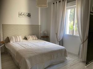 a white bedroom with a large bed and a window at Villa sept fonds in Royan
