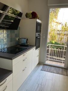 a kitchen with white cabinets and a large window at Villa sept fonds in Royan