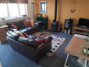 a living room with a leather couch and a table at Charming Cabin near Snowdonia National Park in Caernarfon