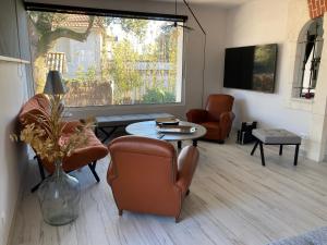 ein Wohnzimmer mit Stühlen, einem Tisch und einem Fenster in der Unterkunft Villa sept fonds in Royan