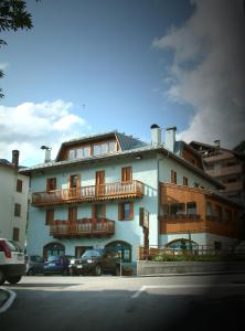 a large building with balconies and cars parked in front of it at Residenza Domino in Selva di Cadore