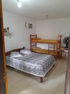 a bedroom with a bed and a table and a desk at Chalézinho - Massaguaçu in Caraguatatuba