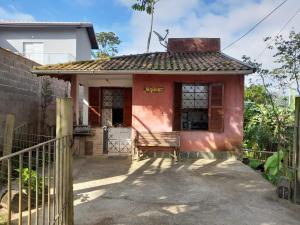 a small red house with a fence in front of it at Chalézinho - Massaguaçu in Caraguatatuba