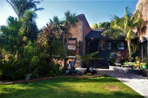 une maison en briques avec des palmiers dans la cour dans l'établissement 9 Serendipity Stay, à George