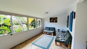 ein Wohnzimmer mit 2 Stühlen und 2 Fenstern in der Unterkunft Villa La Caze Plain'itude Saint Paul in Saint-Paul