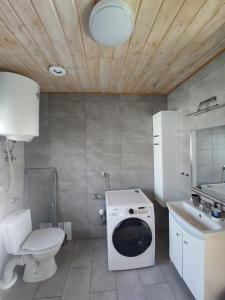 a bathroom with a washing machine and a sink at Domki Komfort całoroczne in Zator