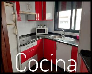 una piccola cucina con armadi rossi e forno a microonde di Casa Santa Tecla A Guarda ad A Guarda