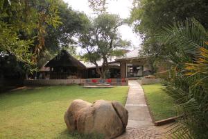 a house with a large rock in front of a yard at Idube Game Reserve in Sabi Sand Game Reserve