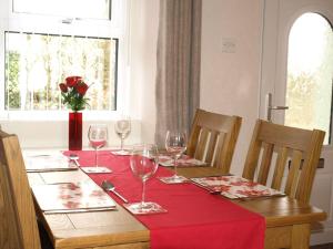 uma mesa com copos de vinho e uma toalha de mesa vermelha em Pinfold Cottage on the edge of lake district em Bothel