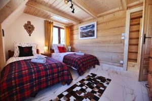 Duas camas num quarto com paredes de madeira em WILLA SZELIGÓWKA KOŚCIELISKO em Kościelisko