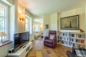 a living room with a flat screen tv and a chair at Ferienwohnung Dünenblick in Sankt Peter-Ording