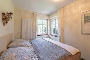ein Schlafzimmer mit einem Bett und zwei Fenstern in der Unterkunft Ferienwohnung Dünenblick in Sankt Peter-Ording