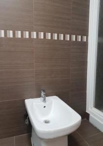 La salle de bains est pourvue d'un lavabo blanc et de carreaux bruns. dans l'établissement PIEDAD FERNANDEZ FERNANDEZ GESTION DE INMUEBLES - III, à O Barqueiro
