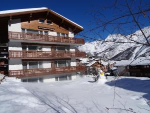 un bâtiment dans la neige avec des montagnes en arrière-plan dans l'établissement Apartments Alpenfirn Saas-Fee, à Saas-Fee