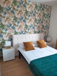 een slaapkamer met een wit bed en tropisch behang bij charmant T2 formiguères les esplaneilles in Formiguères