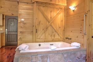 ミラーズバーグにあるWild Cherry Treehouse by Amish Country Lodgingの納屋のドア付きの客室で、バスタブが備わります。