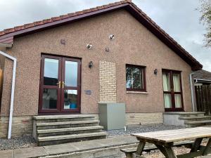 a house with a picnic table in front of it at Four-Bedroom House - Stratherrick Free Parking in Inverness