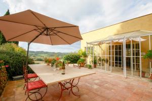 a patio with a table and an umbrella at Villa Ginevra by Tenuta di Ghizzano in Ghizzano
