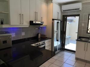 a kitchen with white cabinets and black counter tops at Mtunzi Park, 39 Peaceful shores in Scottburgh