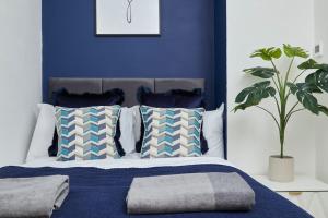 a blue bedroom with a bed with pillows and a plant at Beautiful Central Apartment in Leamington Spa