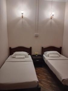 2 camas en una habitación con 2 lámparas en la pared en Margereth Cottage, en Kuala Penyu