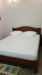 1 cama con sábanas blancas y almohadas en una habitación en Margereth Cottage, en Kuala Penyu