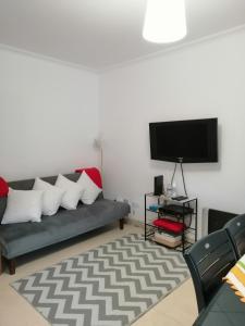 uma sala de estar com um sofá e uma televisão de ecrã plano em PENICHE - Guest House Casa das Estelas em Peniche