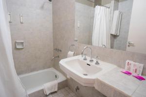 a white bathroom with a sink and a bath tub at Hotel Posada Del Sol in Salta +59 photos