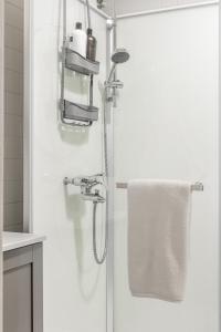 ein weißes Bad mit einer Dusche und einem Handtuch in der Unterkunft Comfortable city home in Helsinki + 16 Fotos