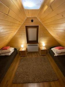 Pokój z 2 łóżkami i telewizorem w drewnianym pokoju w obiekcie Luxdomki w Krasnobrodzie