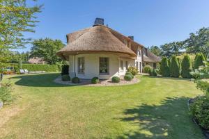 uma casa com telhado de palha e um grande quintal em Feriewohnung Kaminstuv em Sankt Peter-Ording