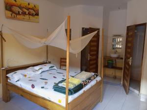 a bedroom with a bed with a mosquito net at Guesthouse Dalal ak Jàmm in Mbour