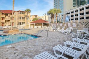 a pool with white chairs and a group of tables and chairs at Waipani A-18 in Myrtle Beach