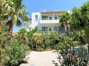 a white building with palm trees and flowers at Hotel Plakures in Falasarna