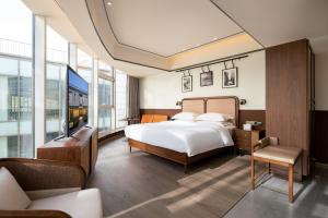 um quarto com uma cama, uma televisão e um sofá em 时光赞歌花园酒店北京大兴旧宫旺兴湖公园店 em Pequim